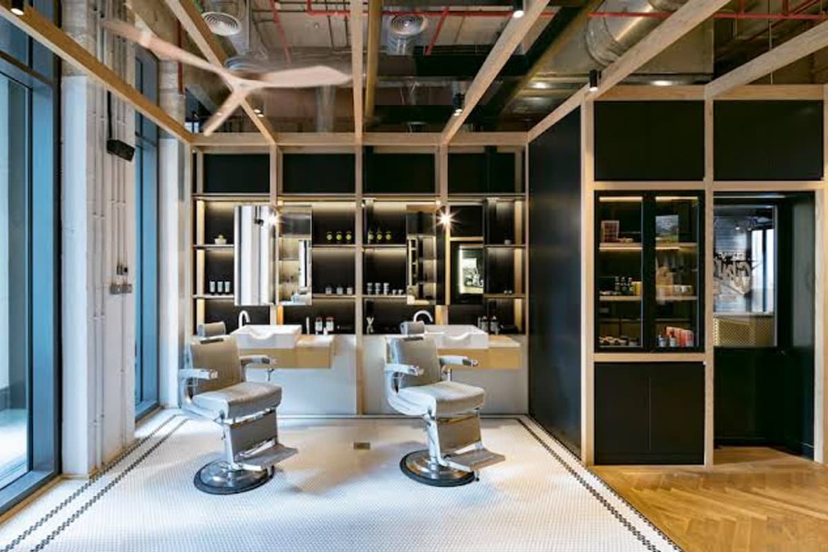 A barbershop with two chairs facing the mirrors, basins between them, nobody in the seats.