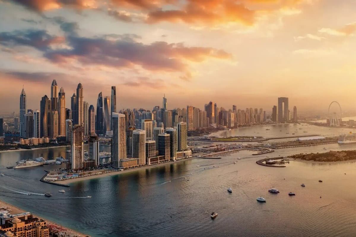 The Dubai Marina skyline at sunset, towers along the water with boats moored below.