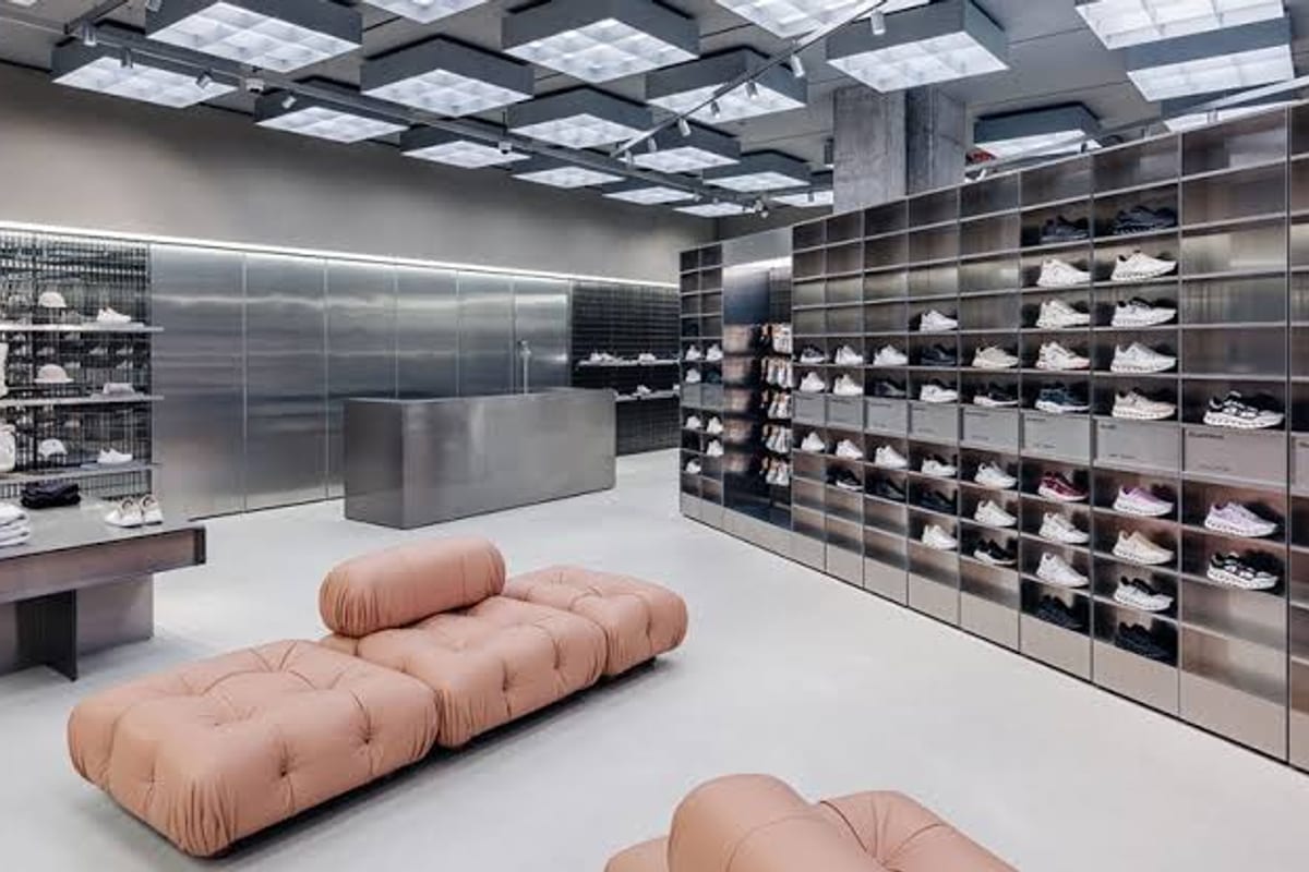 A shoe showroom: trainers in lit alcoves along a full wall, seating on the floor, nobody in the room.